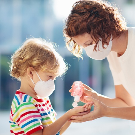 Dental team member putting antibacterial sanitizer on child's hand