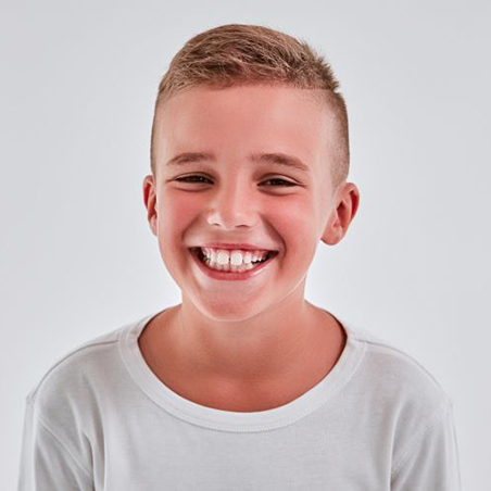 Portrait of smiling young boy against gray background