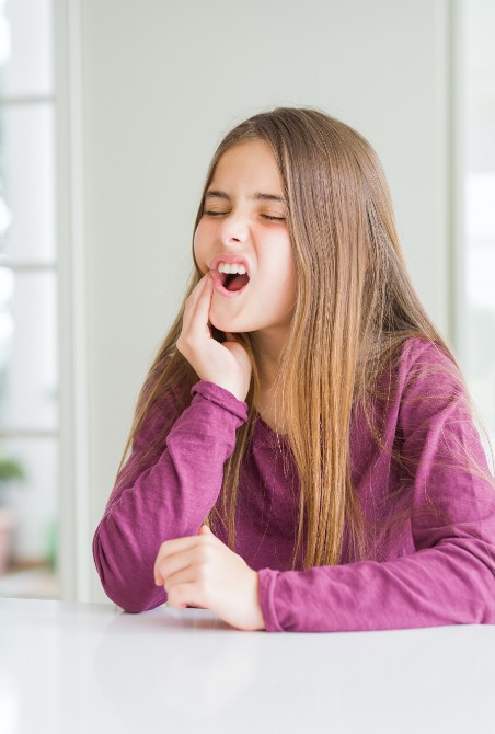 Child in need of emergency dentistry holding jaw