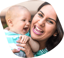 Mother holding smiling baby after dentistry for infants