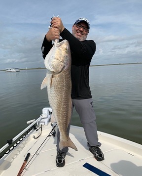 Doctor Pearson holding a large fish on a deep sea fishing trip