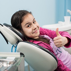 Young girl at cleaning and checkup appointment, giving thumbs up