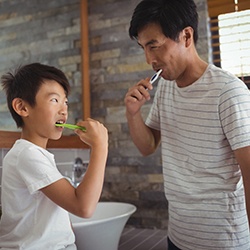 Father and son brushing teeth together in bathroom