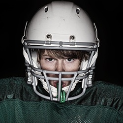 Teen football player in green jersey, wearing mouthguard