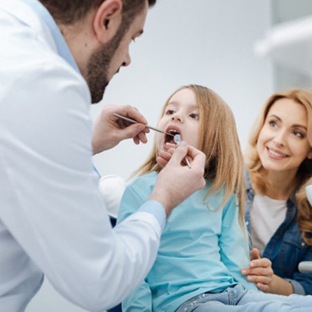 Wylie dentist examining young girl’s teeth in dental office