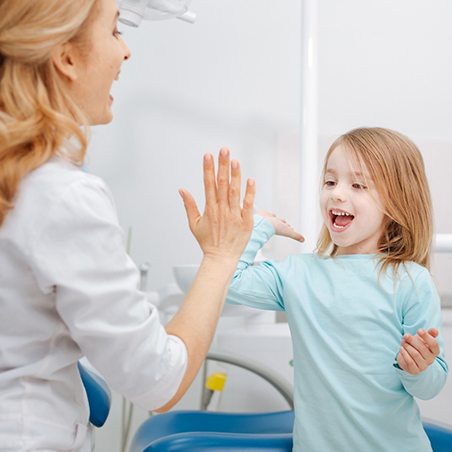 Little girl high-fiving dental team member after receiving sealants
