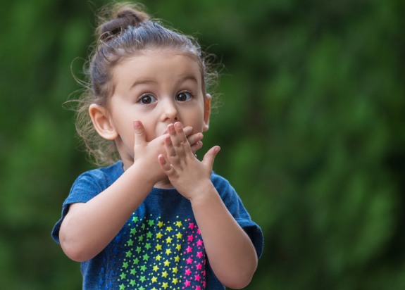 Little girl in need of emergency kids' dentistry covering her mouth