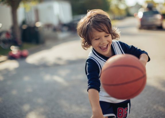 Little boy playing basketball after restorative dentistry