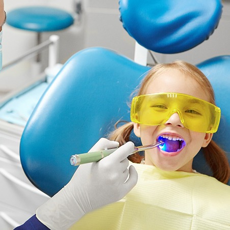 a pediatric dentist and a child sitting in a treatment chair, smiling