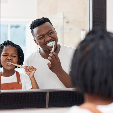 a father brushing his teeth with his daughter