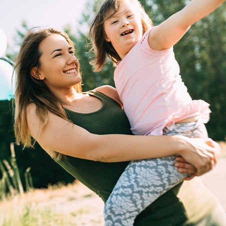 Mother holding smiling child after special needs dentistry