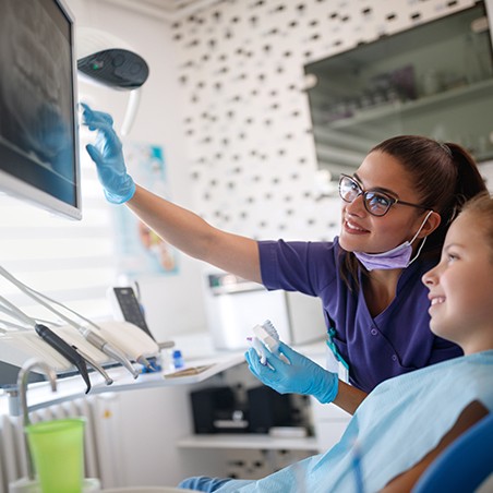 Dental team member and patient looking at periapical x-rays