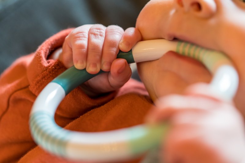 A closeup of a baby biting a teething ring