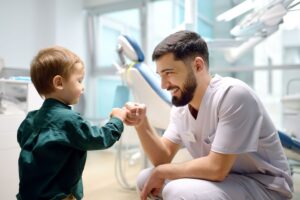 Little boy in green shirt fist-bumping dentist