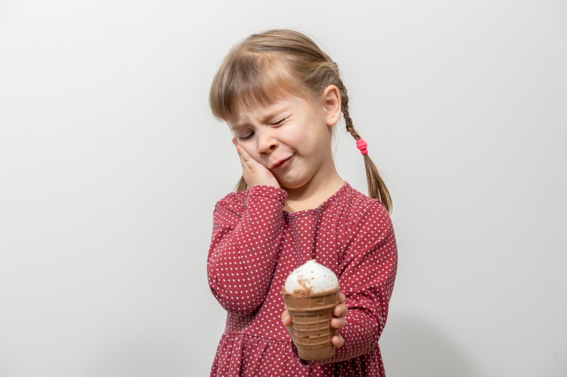 Child holding their cheek needing pulp treatment