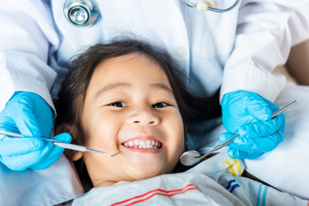 Dentist holding instruments close to little girl's smiling face