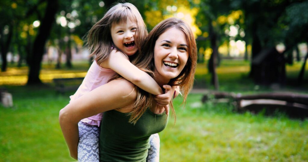 Woman smiling with little girl riding on her back